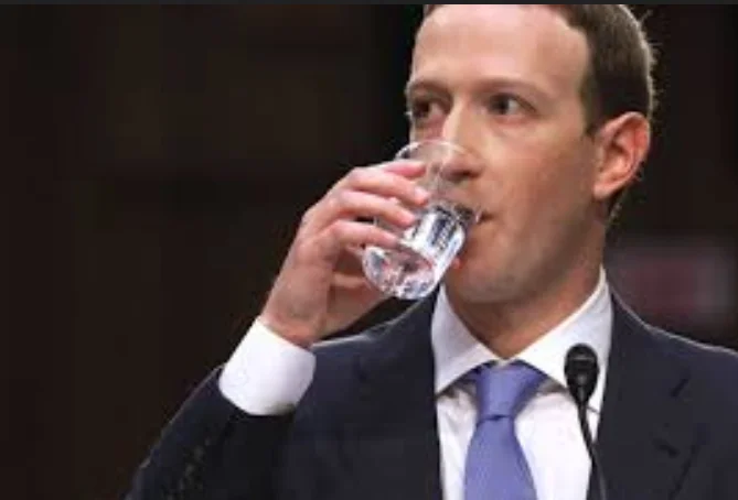 A photo of Mark Zuckerberg in a black suit with a blue tie, nervously drinking a glass of water in front of the supreme court.
